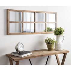 a wooden table topped with a clock next to a mirror and potted plant on top of it