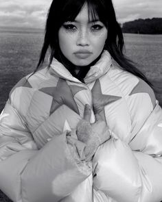 a black and white photo of a woman wearing a jacket with stars on the front