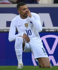 a soccer player sitting on the ground with his hand to his face while looking down