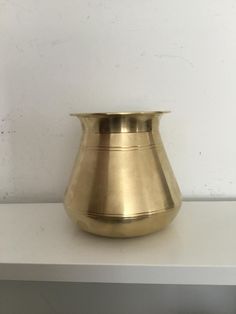 a gold vase sitting on top of a white shelf