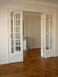 an empty room with white doors and wood floors