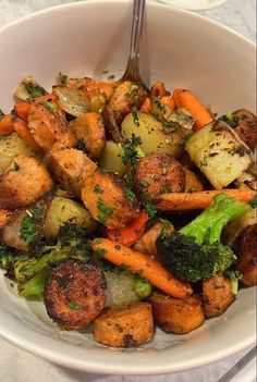 a white bowl filled with cooked vegetables on top of a marble countertop next to a fork