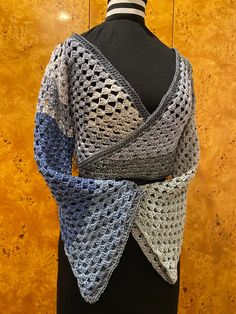 a mannequin wearing a blue and gray knitted shawl on top of a black dress