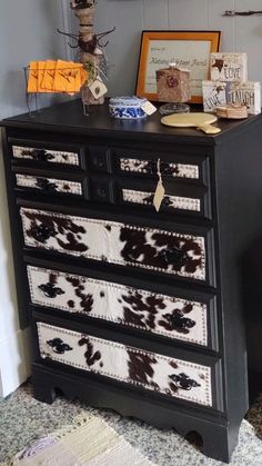 a black dresser with brown and white cow print drawers