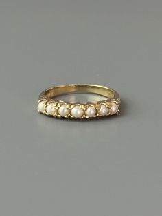 Size: 6.5US Weight: 1.9g Dimensions: 1/8" tall Hallmarks: 10K This sweet little pearl ring is in the style of a half eternity ring and hails from the mid century.  Seven luscious and lucky whole pearls nestle inside 10k yellow gold. This ring makes a great stacking ring with gold bands and other gold gemstone rings. Excellent condition.  Patina as found Expanded shop policies under FAQ Formal Stackable Pearl Ring Fine Jewelry, Formal Stackable Pearl Ring, Fine Jewelry, Classic 14k Gold Stackable Pearl Ring, Stackable Pearl Ring For Formal Events, Stackable Pearl Ring For Formal Occasions, Classic Stackable Pearl Ring, Classic Stackable Pearl Ring For Formal Occasions, Vintage Stackable Rings For Formal Occasions, Vintage Half Eternity Jewelry As A Gift