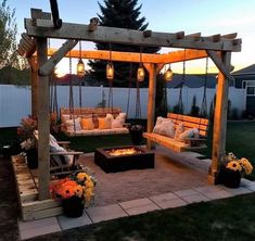 an outdoor living area with swings, chairs and fire pit in the middle of it