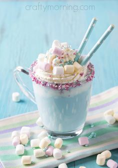 a cup filled with marshmallows on top of a blue tablecloth and candy