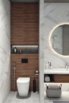 a white toilet sitting next to a bathroom sink under a round mirror on a wall