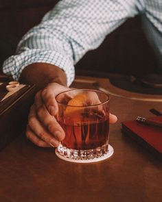 a man holding his hand over a glass of alcohol