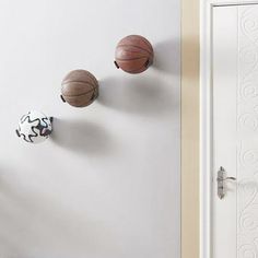 three basketballs are hanging on the wall next to a door with two balls in it