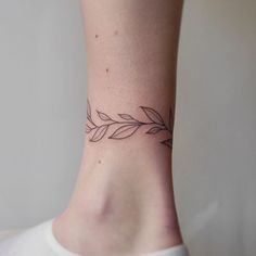 a woman's foot with a small tattoo on the side of her ankle that has leaves growing out of it