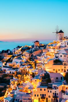 an aerial view of a town with windmills on top at night, overlooking the ocean