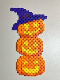 a perler bead pattern of a pumpkin wearing a witch's hat on a white surface