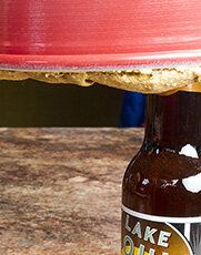 a bottle of cake batter sitting on top of a counter next to a red plate