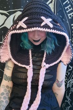 a woman with green hair wearing a black crocheted hat and pink braids