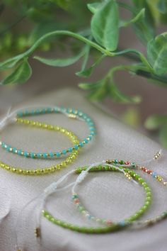 two bracelets sitting on top of a white cloth next to a potted plant