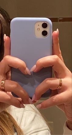 a woman holding up her phone in front of her face and showing it to the camera