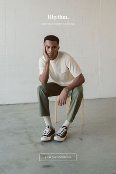 a man sitting in a chair with his hand on his chin and looking at the camera