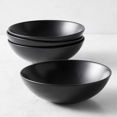 three black bowls sitting side by side on a white surface