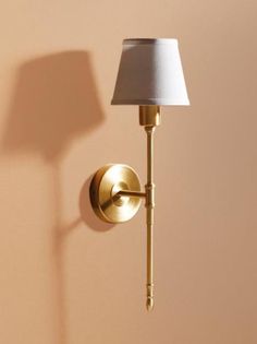 a wall lamp with a white shade on it next to a beige wall and floor