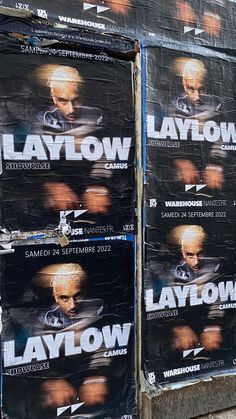 several large posters are stacked up on the side of a building in front of a man's face