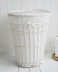 a white wicker basket sitting on top of a wooden floor next to a candle