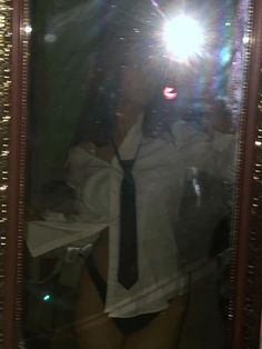 a woman is taking a selfie in front of a mirror with her tie on