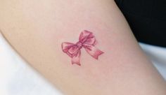 a woman's arm with a pink bow tattoo on the left side of her body