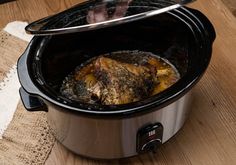 a slow cooker filled with food on top of a wooden table