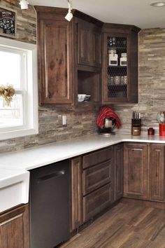 a kitchen with wooden cabinets and white counter tops in front of a brick wall that has wine bottles on it