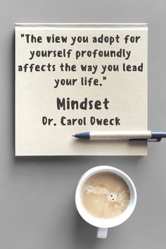 a cup of coffee sitting on top of a table next to a note that reads, the view you adopt for yourself professionally affects