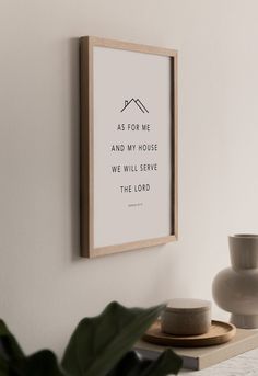 a framed print on the wall above a table with two vases and a potted plant