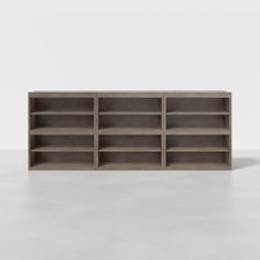 an empty bookcase on a white surface with no people around it and one person standing in front of the bookshelf