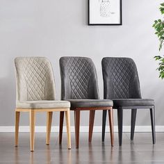 three chairs are lined up next to each other in front of a wall with a plant