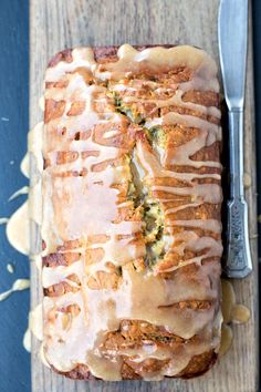 a loaf of bread covered in icing next to a knife