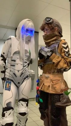 two cosplays dressed in costumes standing next to each other on a tiled floor