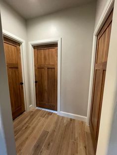 an empty room with two wooden doors and hard wood flooring on the other side