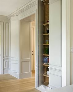 an open closet in the corner of a room with white walls and wood flooring