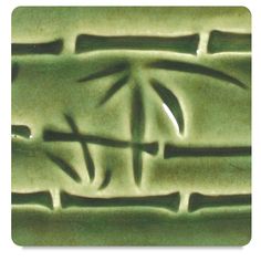 a green ceramic tile with an artistic design