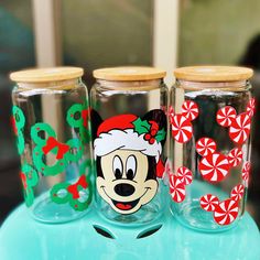 three glass jars decorated with mickey mouse faces and candy canes on a blue table