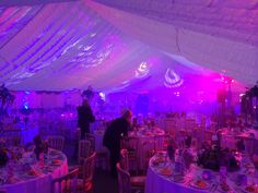 the inside of a large tent with tables and chairs set up for an evening party