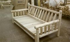 a white wooden bench sitting next to stacks of wood planks in a warehouse filled with lumber