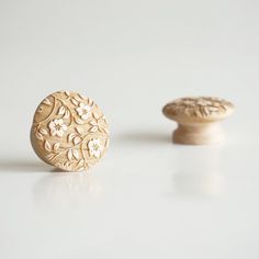 two wooden knobs sitting on top of a white table next to each other and one is carved with flowers