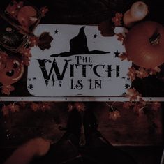 a sign that says the witch is in surrounded by pumpkins