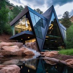 an unusual house with a pond in front of it and large rocks around the pool