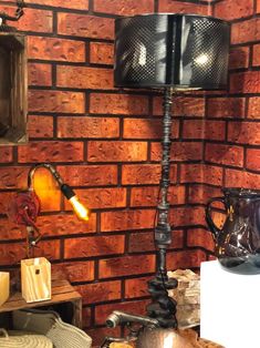 a lamp that is on top of a table next to a brick wall with other items around it