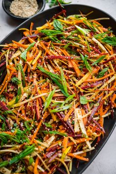 a black plate topped with carrots and green beans