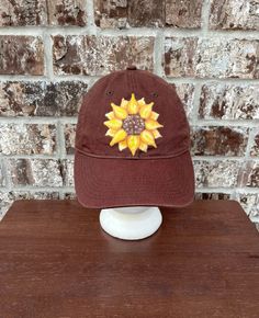 "Authentic Pigment cotton baseball cap in brown with a hand painted sunflower.  Washed multiple times for a unique faded look 100% cotton twill 6-panel, unstructured sewn eyelets self-fabric closure with D-ring slider and tuck-in strap One Size Hat Band 22.8\" These are great hats! My family has worn them for years. I wash them in cold water on the gentle cycle. Visit my new glassware shop https://www.etsy.com/shop/kitchenbarhomedecor for unique gifts for your home! Follow me on Instagram http://www.instagram.com/gulflifebynichole" Brown Cotton Trucker Hat With Curved Bill, Vintage Brown Dad Hat With Curved Bill, Brown Cotton Trucker Hat One Size, Brown Country Style Baseball Cap With Curved Brim, One Size Brown Cotton Trucker Hat, Brown Cotton Hats One Size Fits Most, Vintage Brown Cotton Baseball Cap, Vintage Brown Cotton Trucker Hat, Brown Cotton Brimmed Baseball Cap