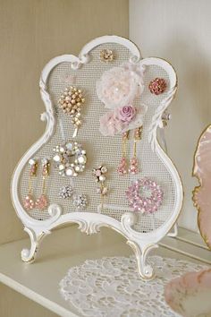 a white shelf topped with lots of earrings and brooches on top of it