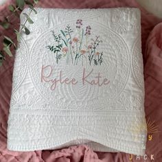 a white quilt with pink flowers on it and the words pride kate written in cursive font